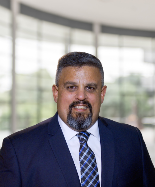 Portrait of Craig Pina, the founder of C. Pina Insurance Agency, dressed in a suit and tie with a professional background.